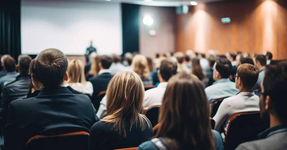 Inscríbete y participa en el V Encuentro Nacional de Datos Abiertos Vista trasera del público en la sala de conferencias; ponente dando una charla en la sala de conferencias durante un evento empresarial.