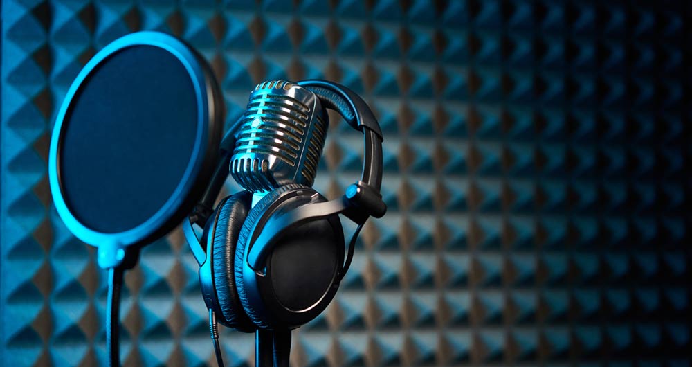 Nuevo episodio del pódcast: OGC API Features y Seccionado Censal del INE Micrófono para grabar podcasts en un estudio con luces de neón.